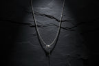 Silver necklace on a white mannequin bust with a blurred indoor background