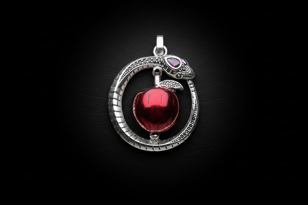 Silver pendant with a red apple on a white background.