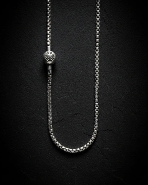 Silver chain necklace on a black textured background