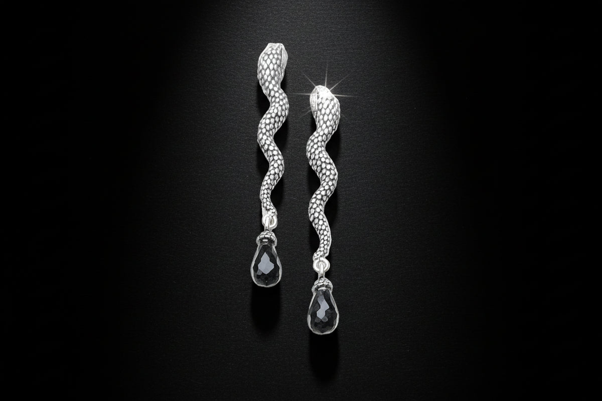 Silver earrings with black beads on a light gray background